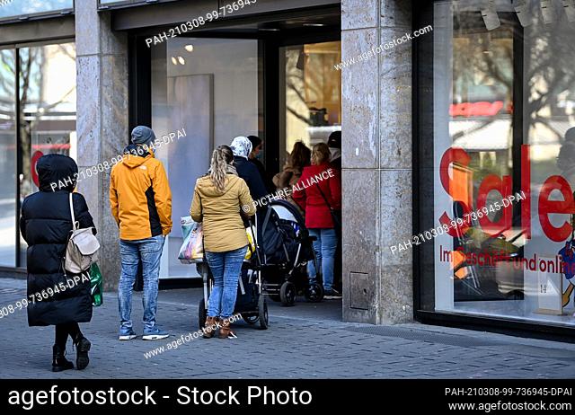 08 March 2021, Saxony, Leipzig: Customers queue outside the entrance of an H&M store in Petersstraße. After a week-long corona-induced lockdown