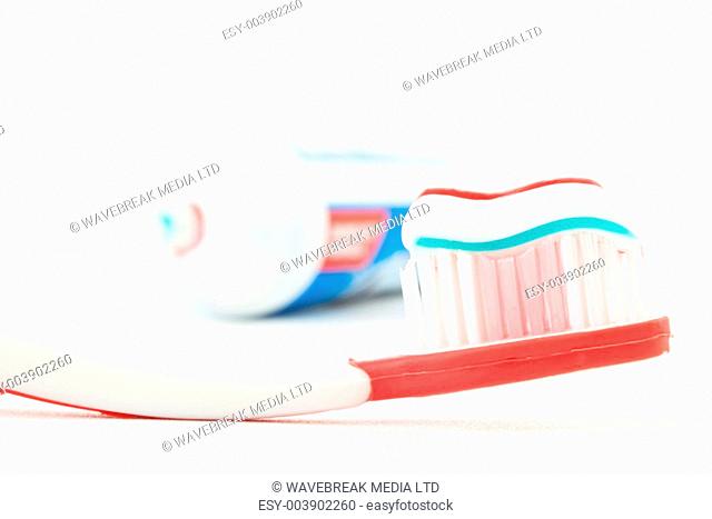 Red toothbrush with toothpaste against white background