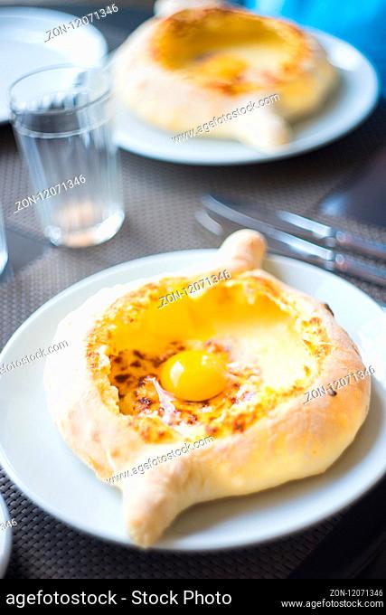 Ajarian or Adjaruli khachapuri, filled with cheese and topped with a raw egg and butter - traditional dish of georgian cuisine
