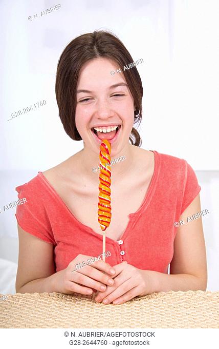 Laughing teenage girl eating a striped lollipop