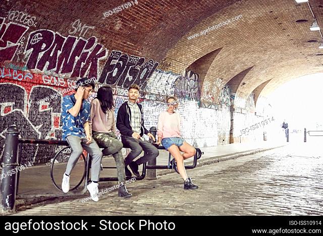 Teenage friends sitting on gate in tunnel