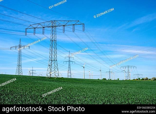 Stromleitungen mit Windturbinen im Rücken in Deutschland gesehen
