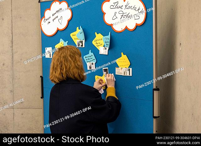 21 January 2023, Saxony, Dresden: A woman puts a piece of paper on a flipchart at the state conference of various organizations for Ukraine aid