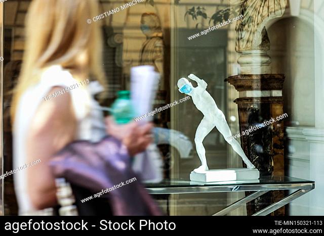 Window of an antique shop, exhibited a small human sculpture with protective mask on the first day with the restrictions of the red zone for the fight against...