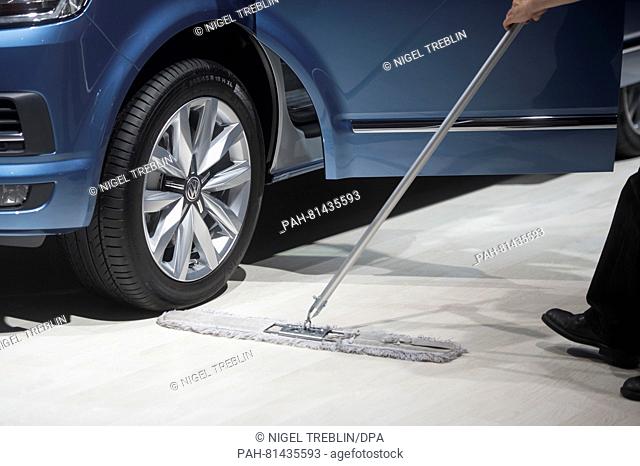 A man cleans the floor in front of a VW Transporter T6 Business at a car exhibition in the context of the shareholder's meeting of Volkswagen AG in Hannover