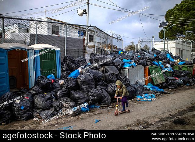 21 January 2020, Greece, Lesbos: A boy plays with a scooter in front of garbage bags in the refugee camp Moria. The camps on the islands of Lesbos, Samos, Chios