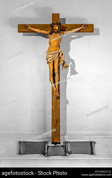 illuminated wooden crucifix in grey ambiance seen in Germany