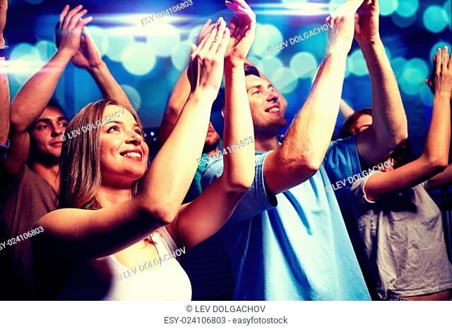 party, holidays, celebration, nightlife and people concept - smiling friends applauding at concert in club