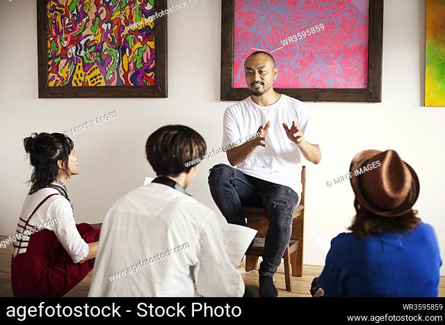 Group of Japanese men and women sitting in art gallery, holding a discussion