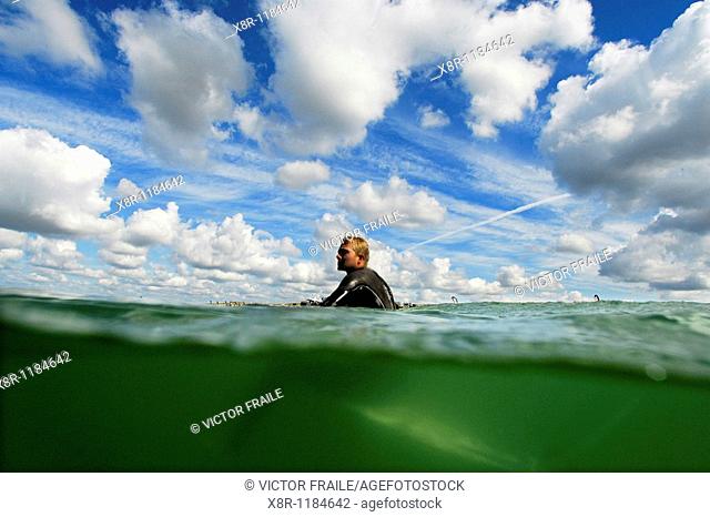 An unidentified surfer sits in his surfboard while he waits for a wave on a warm-up session during the Quiksilver Pro France