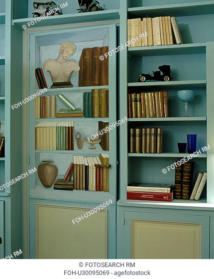 Close-up of pastel blue bookshelves with trompe l'oiel door