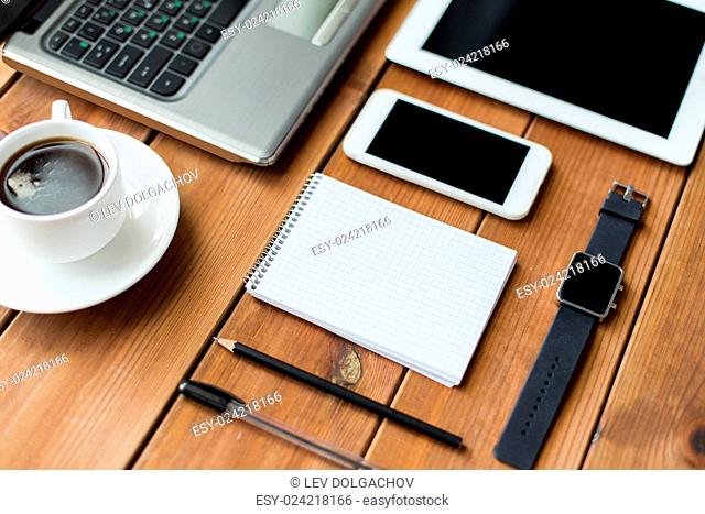 education, business and technology concept - close up of on laptop computer, tablet pc, notebook and smartphone on wooden table