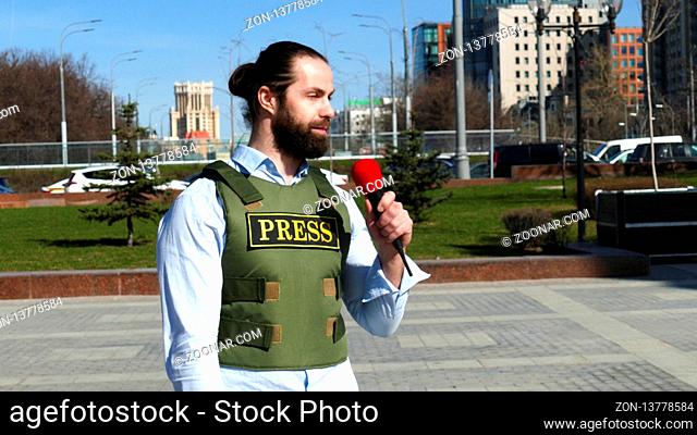 TV Reporter with a microphone wearing a bulletproof vest with press sign