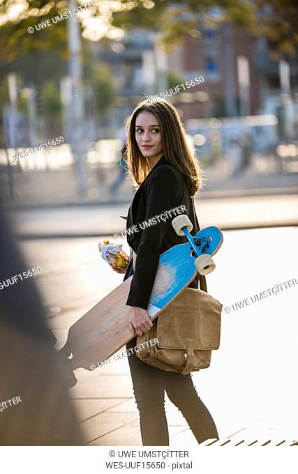 Young woman with longboard in the city on the move
