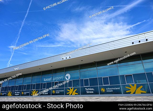 PRODUCTION - 04 August 2022, Hessen, Calden: Clouds and vapor trails hang over the terminal of Kassel Airport. Staff shortages, strikes