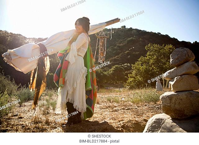 Hispanic woman carrying teepee in desert