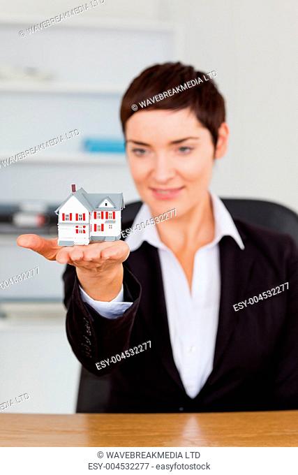 Portrait of a brunette showing a house miniature