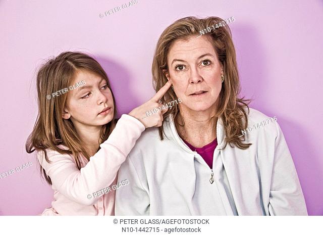 Preteen girl sticking her finger in her mother's ear