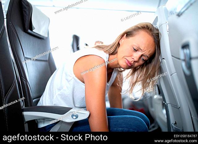 Young happy woman aboard an airplane during flight - not feeling quite well