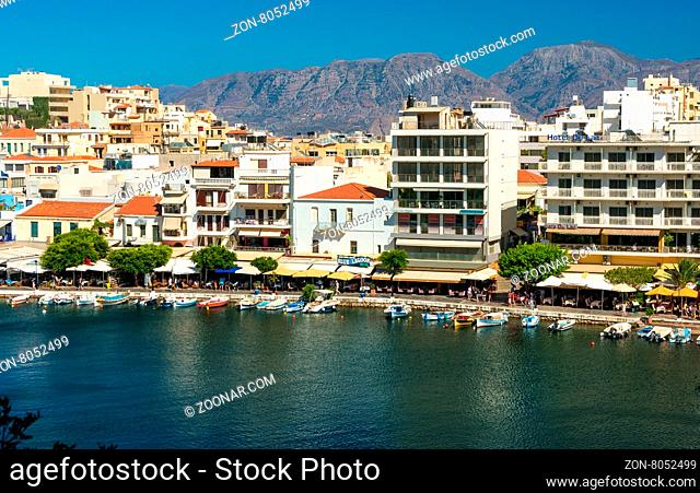 AGIOS NIKOLAOS, GREECE - JULY 20, 2014: Waterfront with outdoor greek tavern, small shops and boats in harbor of Agios Nikolaos, Crete, Greece