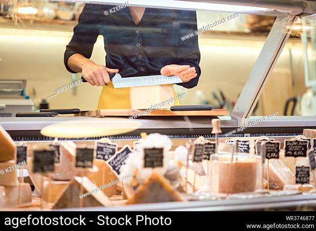 Shop clerk woman sorting cheese in the supermarket display to sell it