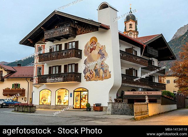 guest house in the old town, behind it church of st. peter and paul at dusk, mittenwald, upper bavaria, bavaria, germany