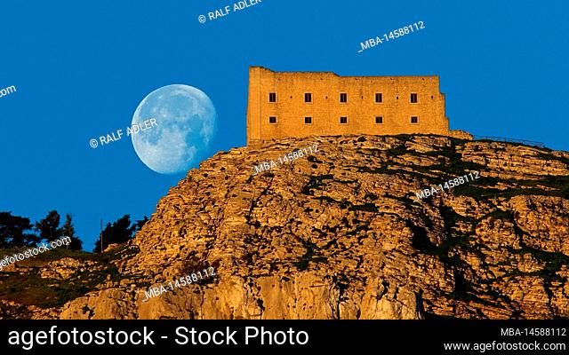 Italy, Sicily, Trapani, Mons Erix, Ancient Erice, morning light, blue sky, fortress building rises on the mountain, behind it the setting full moon