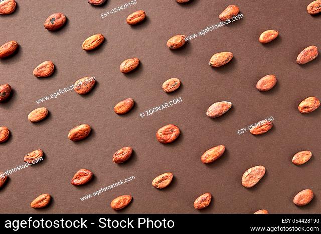 Natural fresh cacao beans on a brown background with soft shadows. Flat lay