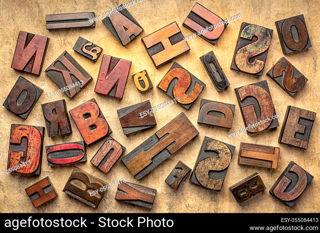 random letters overhead background - vintage letterpress wood type of different fonts (inverted image) against brown handmade bark paper