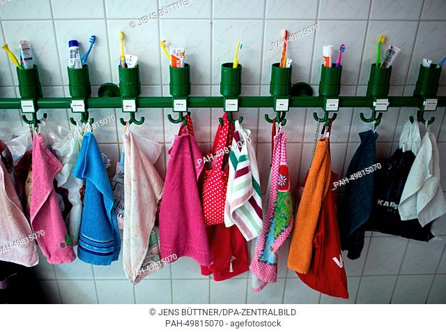 Colourful towels and toothbrush tumblers stand on a shelf in the washing room of the integrated nursery 'Plappersnut' in Wismar, Germany, 19 June 2014