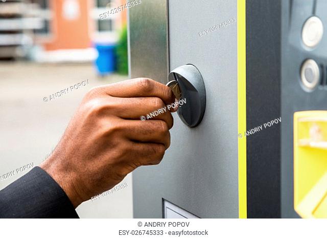 Close-up Of Person's Hand Inserting Coin Into Parking Meter