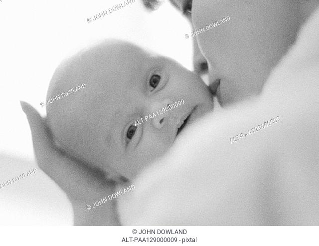 Mother kissing infant's cheek, b&w