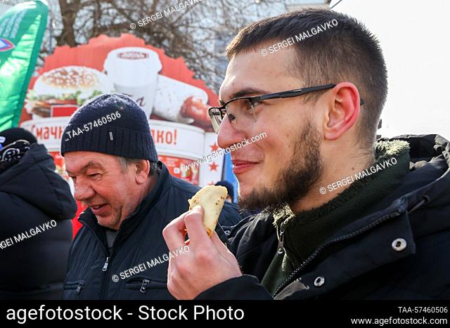 RUSSIA, BERDYANSK - FEBRUARY 20, 2023: People eat blini, traditional Russian pancakes, given out by activists of the Young South public organization during a...