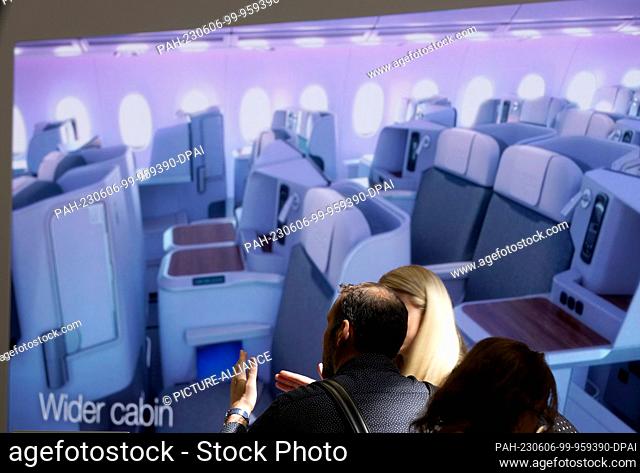 06 June 2023, Hamburg: Trade show visitors stand in front of a screen showing an Airspace cabin at the Airbus booth at the Aircraft Interiors Expo (AIX) in the...