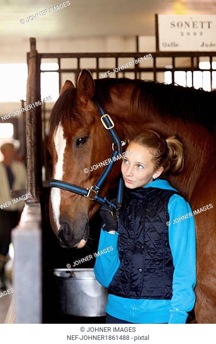 Girl with horse in stable