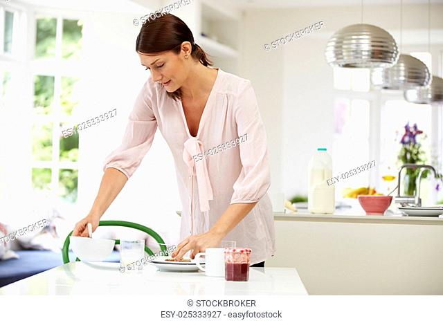 Hispanic Woman Clearing Up After Breakfast