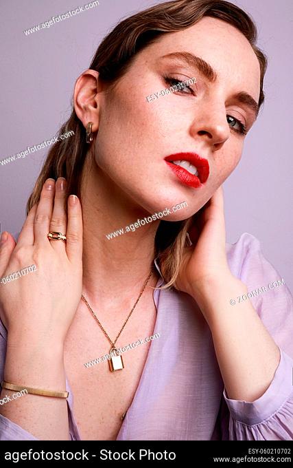 Caucasian young woman wearing golden jewellery posing on colourful wall. Vertical close-up of beautiful woman. High quality photo