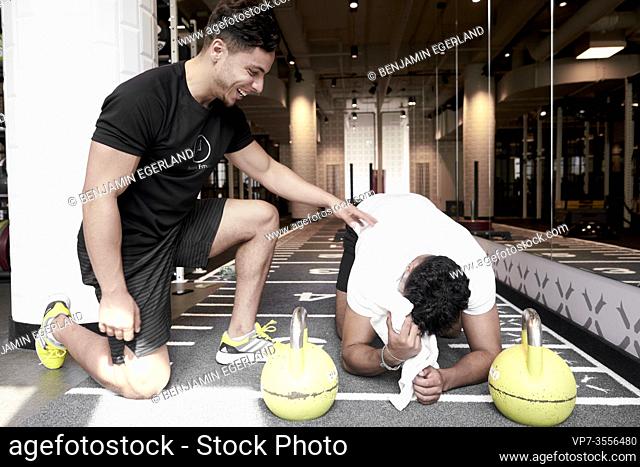 Personal trainer assisting man exercising in gym