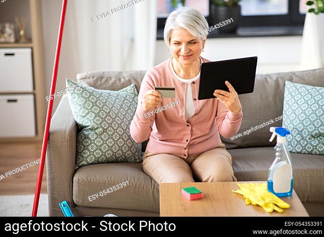 old woman with tablet pc and credit card at home