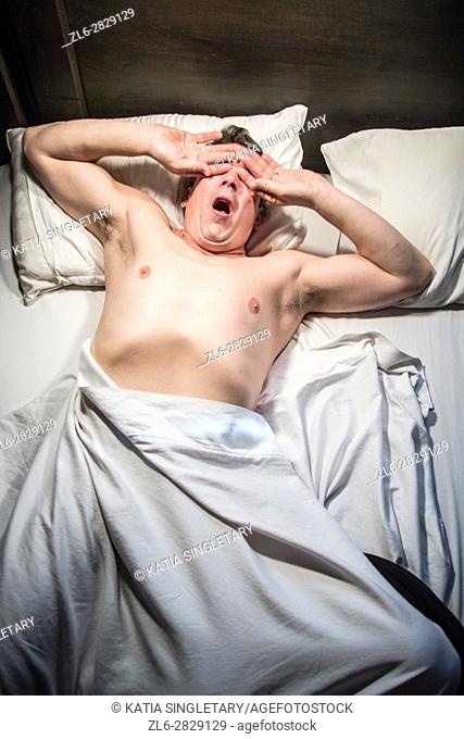 Caucasian male slepping, streching and waking up in bed