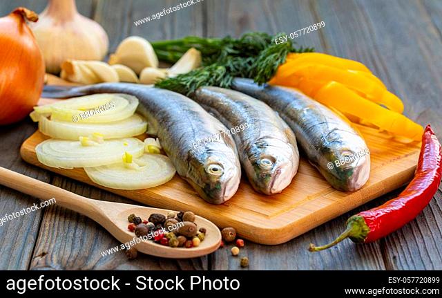 The three trout fish with peppers, onion and garlic on wooden board