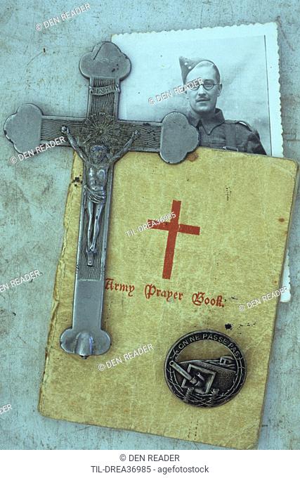Vintage photo of man in World War 2 army uniform lying with grey metal crucifix Army prayer book and Maginot Line badge