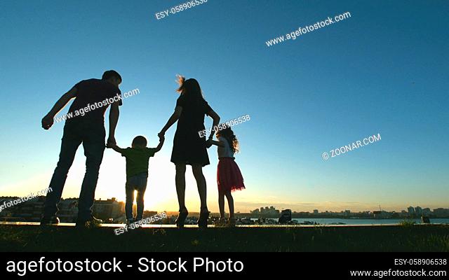 Family at sunset - father, mother, daughter and little son together - silhouette, rear view