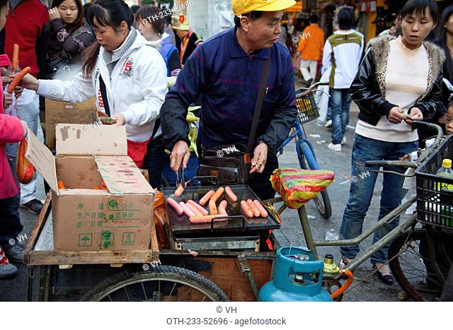 A sausage hawker on the busy Huagai Road shopping walkway at Shunde, Guangdong, China