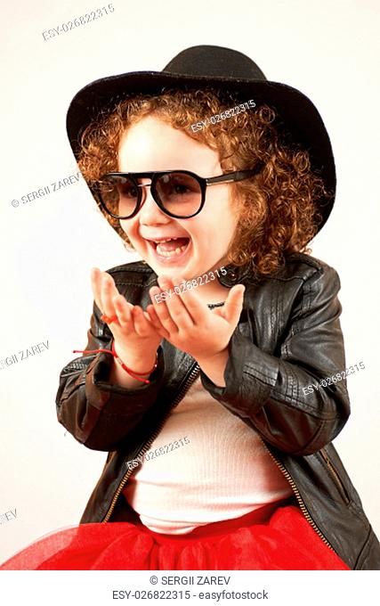 Little girl with black hat and Sunglasses sitting and laughing