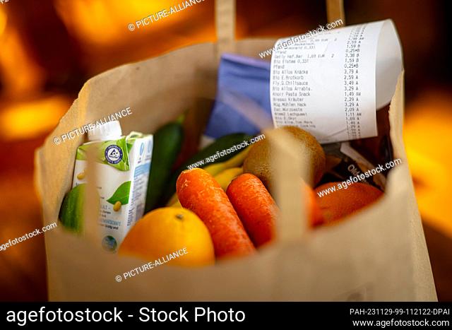 PRODUCTION - 27 November 2023, Bremen: ILLUSTRATION - A receipt lies on top of the groceries in a shopping bag. Inflation in Germany has recently slowed down
