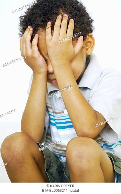 Mixed race boy with head in hands