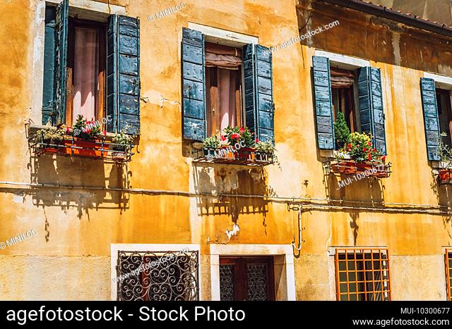 Venice old yellow facade of house with wood windows on the street in Venice Italy