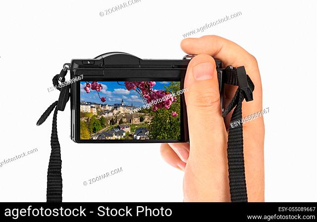 Hand with camera and Luxembourg city cityscape (my photo) isolated on white background
