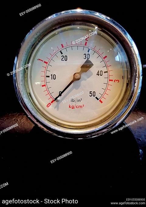 a round shiny pressure gauge with numbers marked in psi and metric on the meter dial on industrial machinery